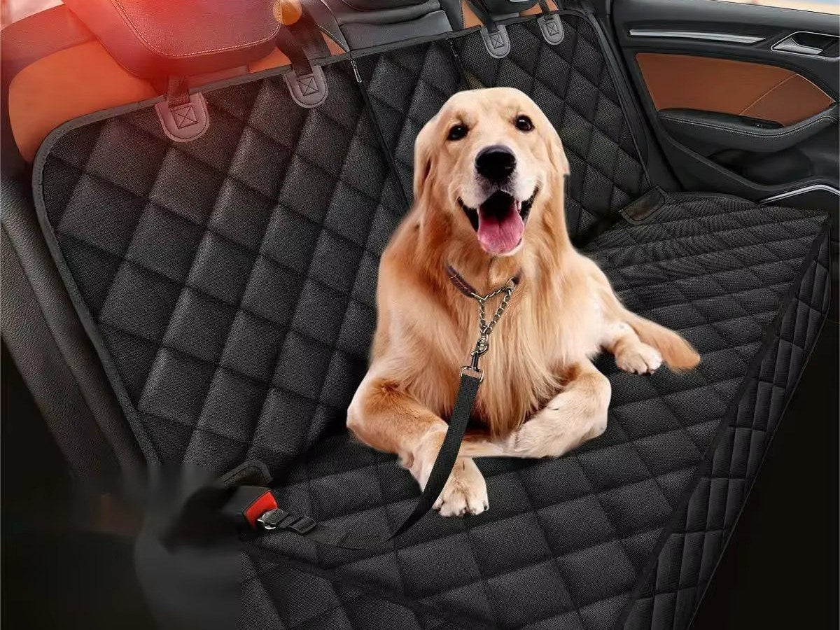 A dog lying on a quilted rear seat protector in the back of a car